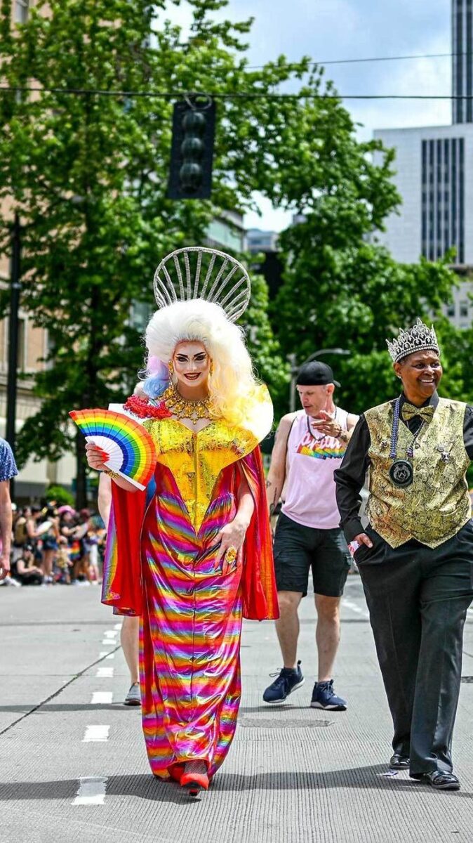 Three members of Pride royalty marching through the street